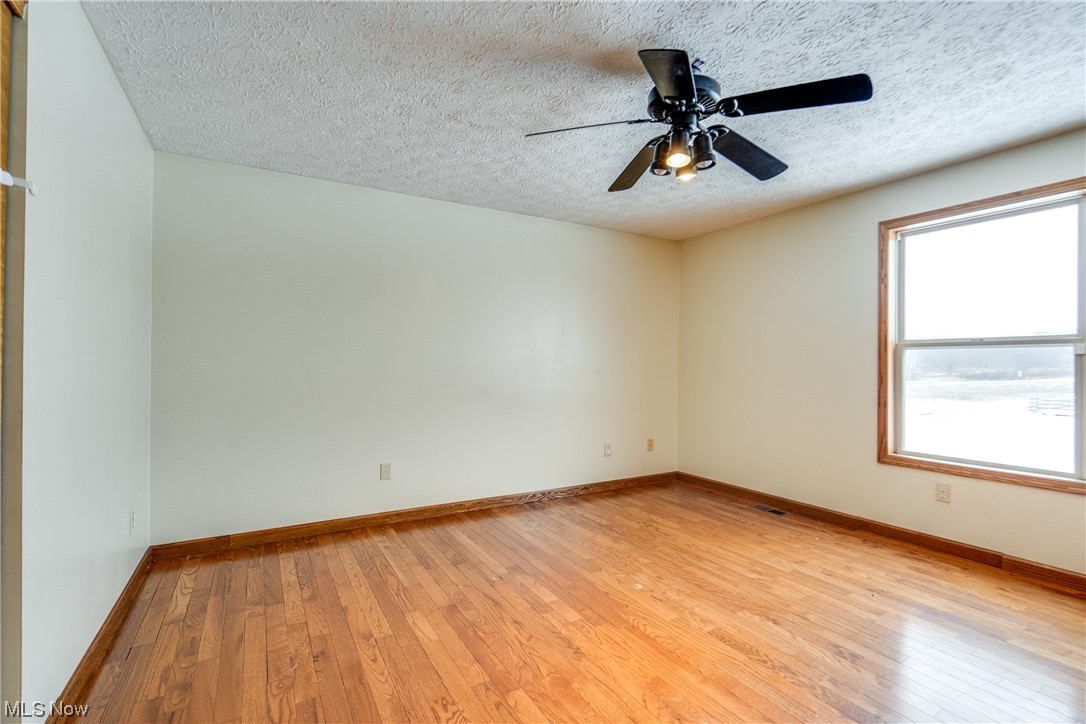 5303 Laubert Road Atwater, OH 44201 - Photo 26 of 37 Empty room featuring ceiling fan, a textured ceiling, light hardwood / wood-style flooring, and a healthy amount of sunlight