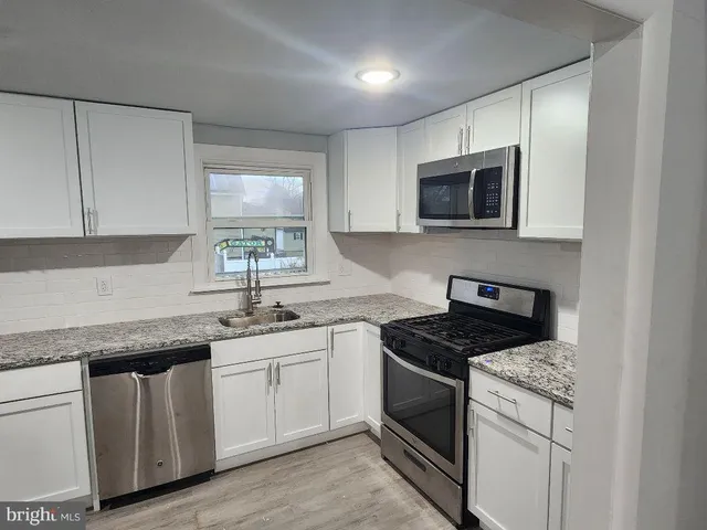 a kitchen with granite countertop white cabinets and white appliances