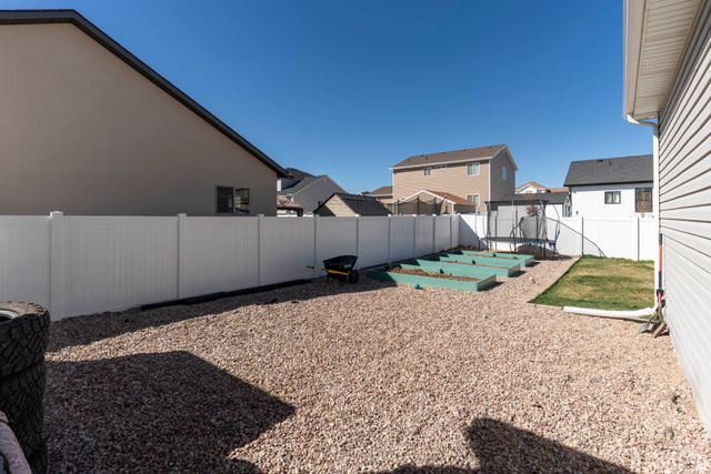 836 South 250 West Vernal, UT 84078 - Photo 50 of 56 Fenced backyard featuring a trampoline, a patio, a residential view, and a garden