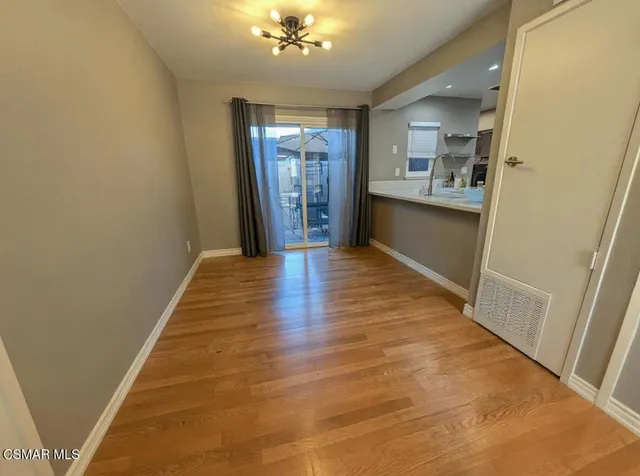 a view of a hallway with wooden floor and a kitchen