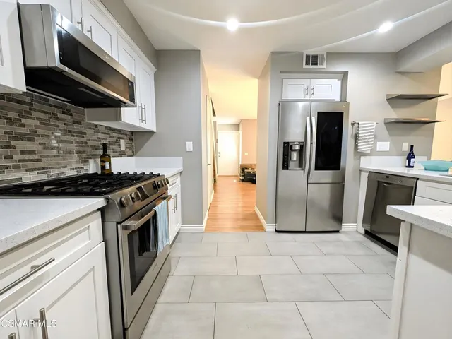 a kitchen with stainless steel appliances granite countertop a stove a refrigerator and a microwave