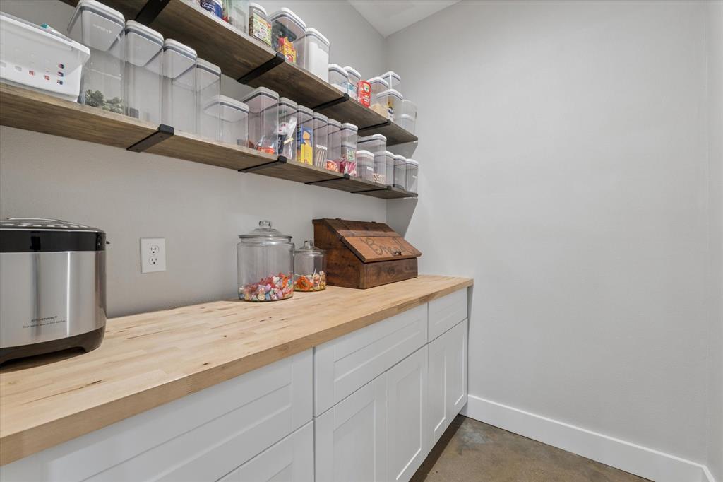 286 Benevolence Way China Spring, TX 76633 - Photo 12 of 37 Pantry featuring extensive wood-finish shelving with black metal supports, white shaker-style cabinetry, and a natural wood-finish countertop