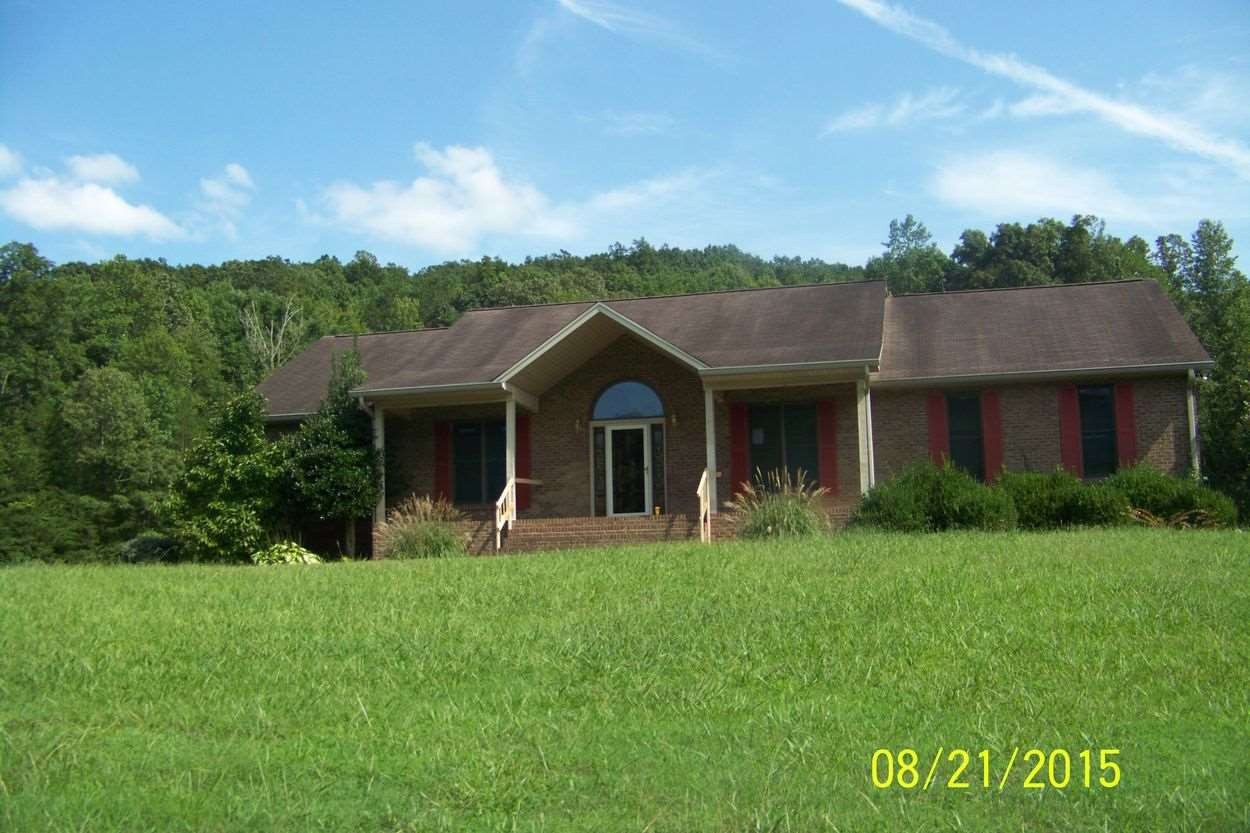 a view of a house with a big yard and large trees