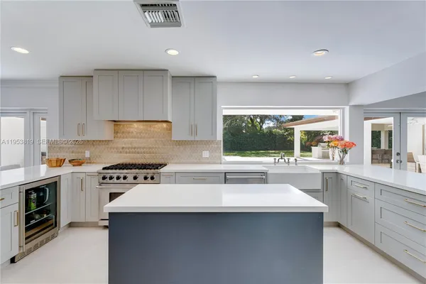 a kitchen with a sink a stove a refrigerator cabinets and a dining table