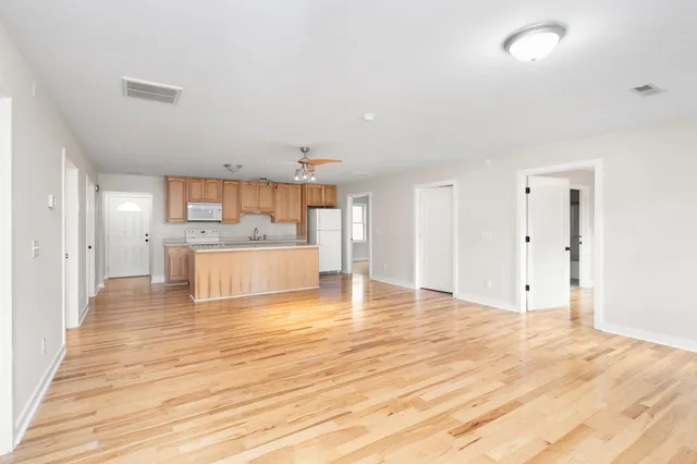 a large kitchen with a stove a sink dishwasher and a refrigerator with wooden floor