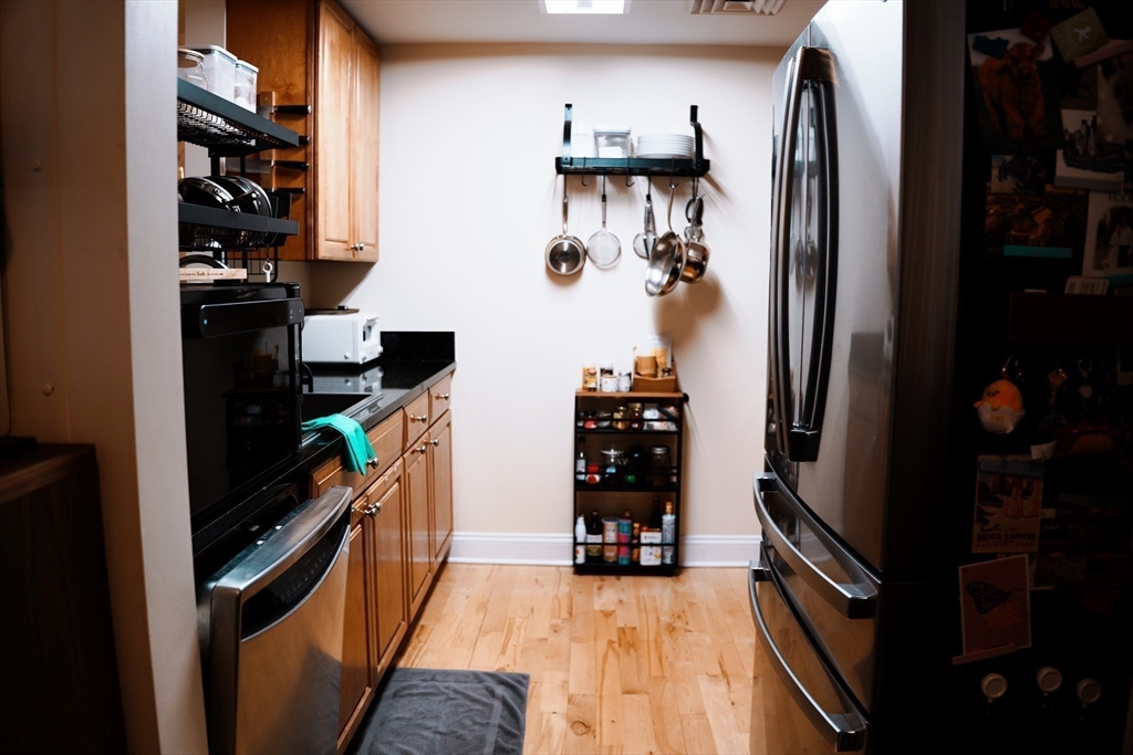 110 Cypress Street, Unit 307 Brookline, MA 02445 - Photo 7 of 24 a kitchen with stainless steel appliances a refrigerator and a wooden floor