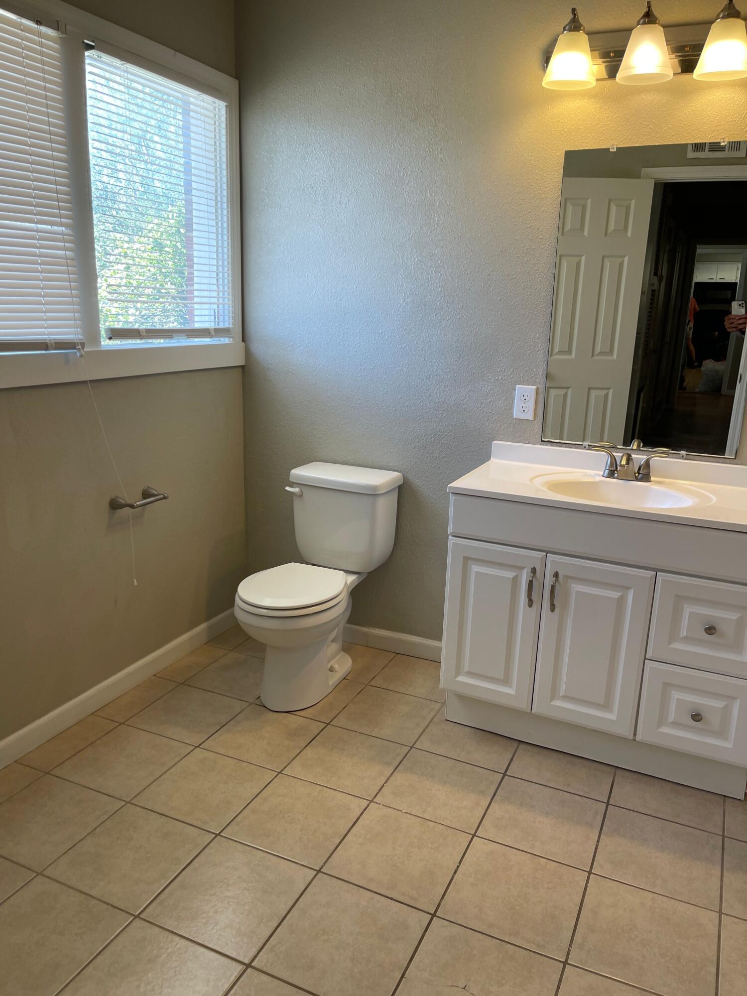 3011 32nd Street Lubbock, TX 79410 - Photo 11 of 16 a bathroom with a toilet a sink and a window