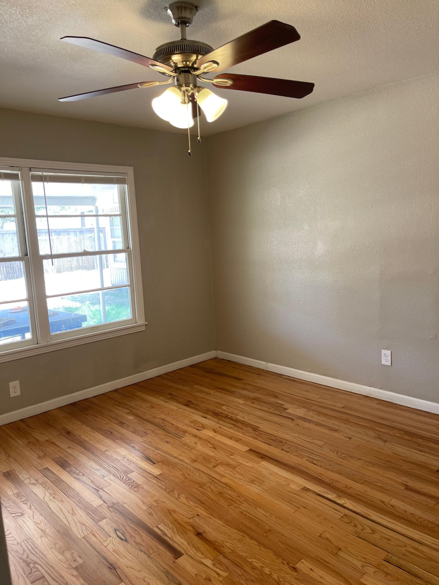 3011 32nd Street Lubbock, TX 79410 - Photo 14 of 16 an empty room with wooden floor fan and windows