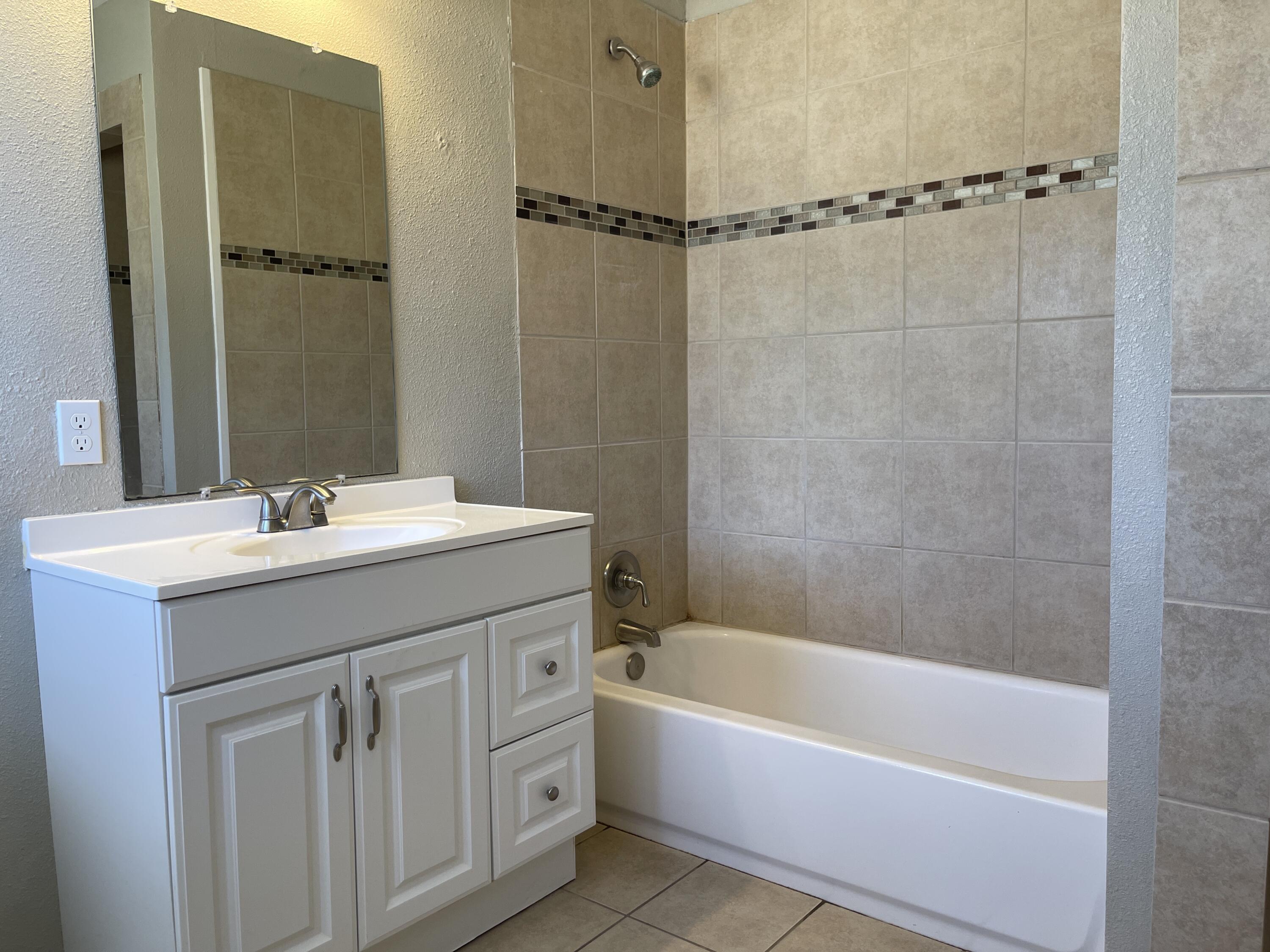 3011 32nd Street Lubbock, TX 79410 - Photo 16 of 16 a bathroom with a sink a mirror a bathtub and shower