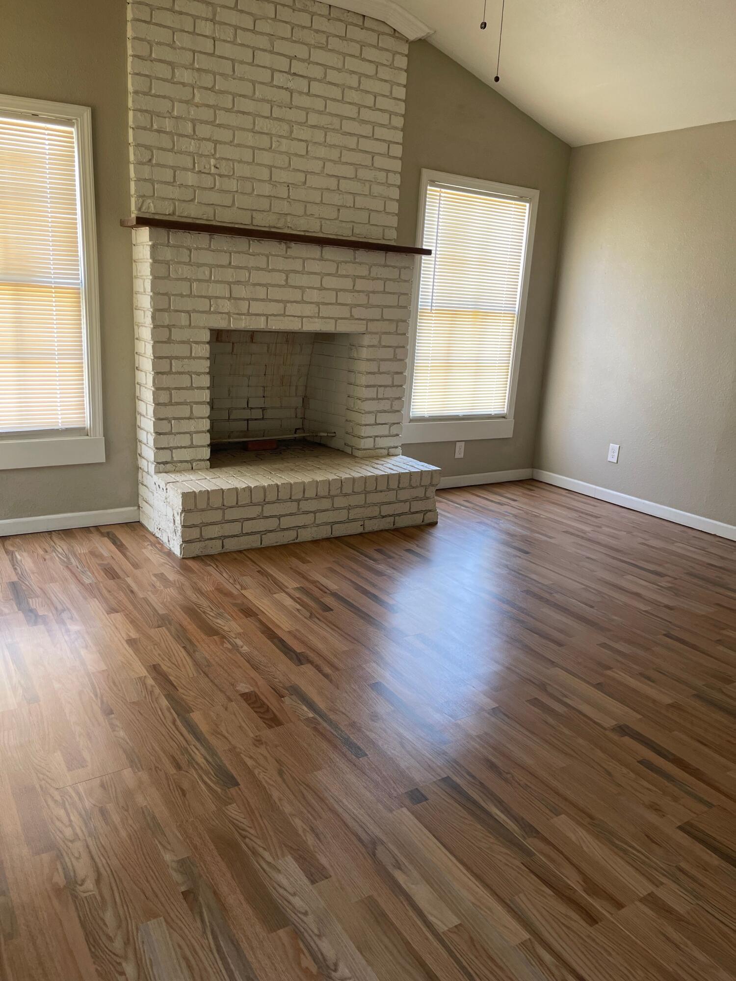3011 32nd Street Lubbock, TX 79410 - Photo 2 of 16 an empty room with wooden floor fireplace and windows