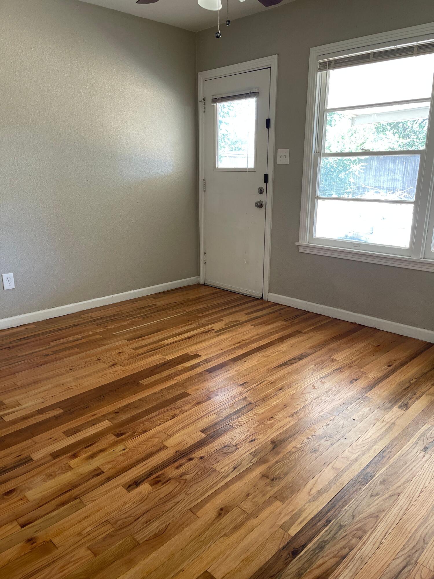 3011 32nd Street Lubbock, TX 79410 - Photo 3 of 16 an empty room with wooden floor and windows