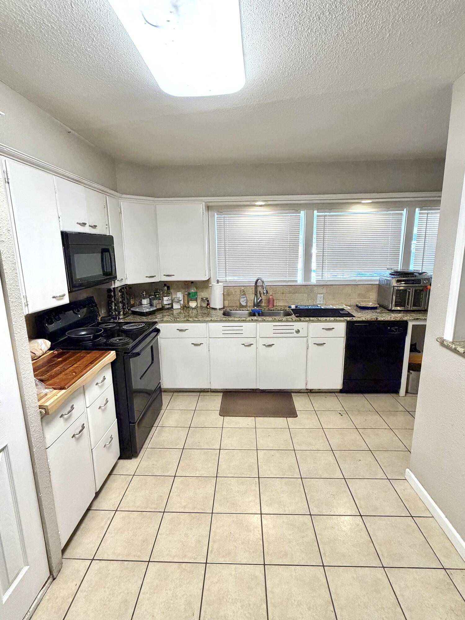 3011 32nd Street Lubbock, TX 79410 - Photo 5 of 16 a kitchen with stainless steel appliances a sink a counter top space cabinets and a large window