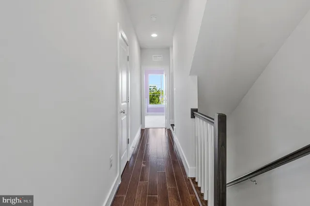 a view of a hallway with wooden floor and staircase