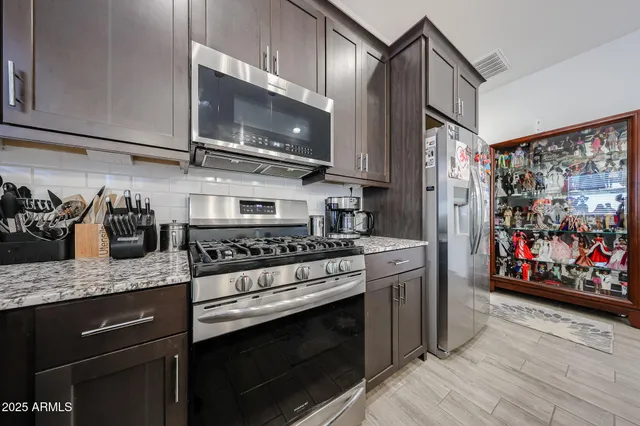 a kitchen with stainless steel appliances granite countertop a stove a sink and a microwave