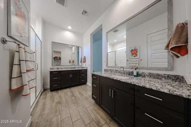 a bathroom with a granite countertop sink mirror and a shower