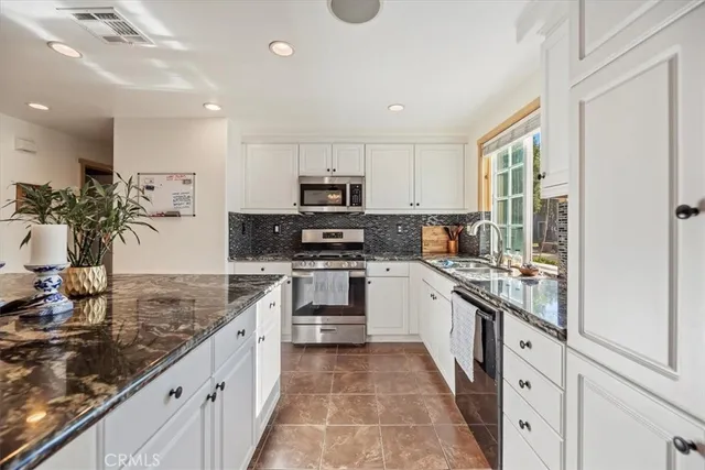 a kitchen with stainless steel appliances granite countertop a refrigerator and a stove top oven