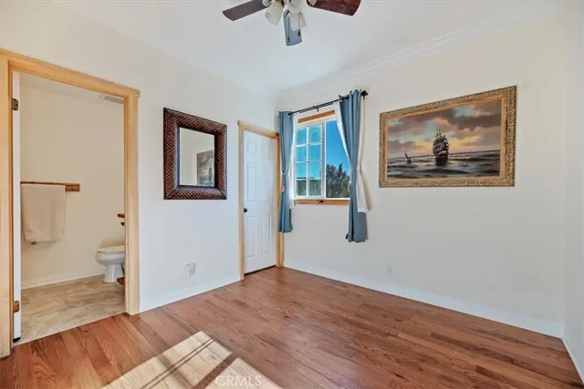 a view of a bedroom with wooden floor and a ceiling fan