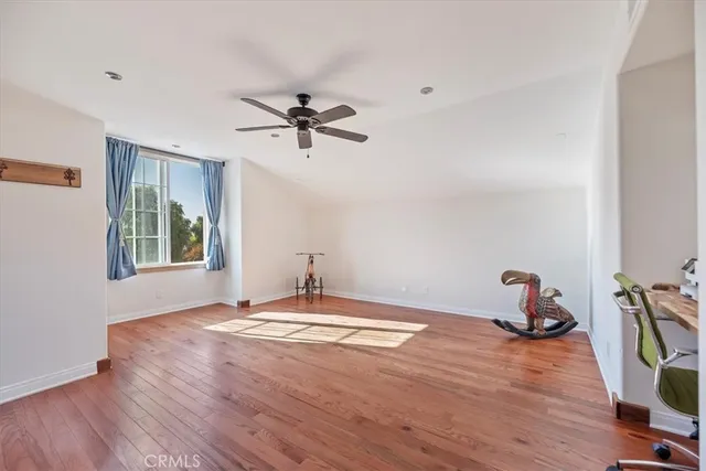 a view of a room with wooden floor and ceiling fan