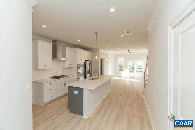 a large white kitchen with a stove a sink dishwasher and a refrigerator with wooden floor