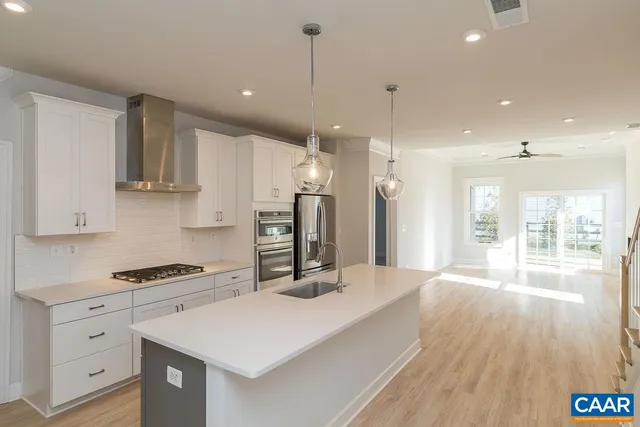 a kitchen with stainless steel appliances kitchen island a sink dishwasher a refrigerator and white cabinets with wooden floor