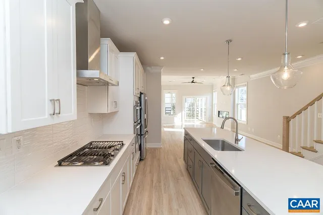 a kitchen with stainless steel appliances a sink a stove a refrigerator and white cabinets