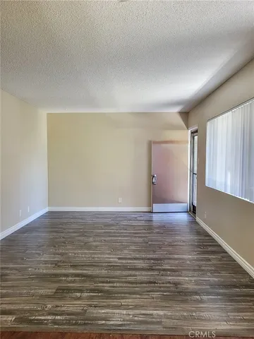 a kitchen with stainless steel appliances granite countertop a refrigerator a sink and white cabinets with wooden floor