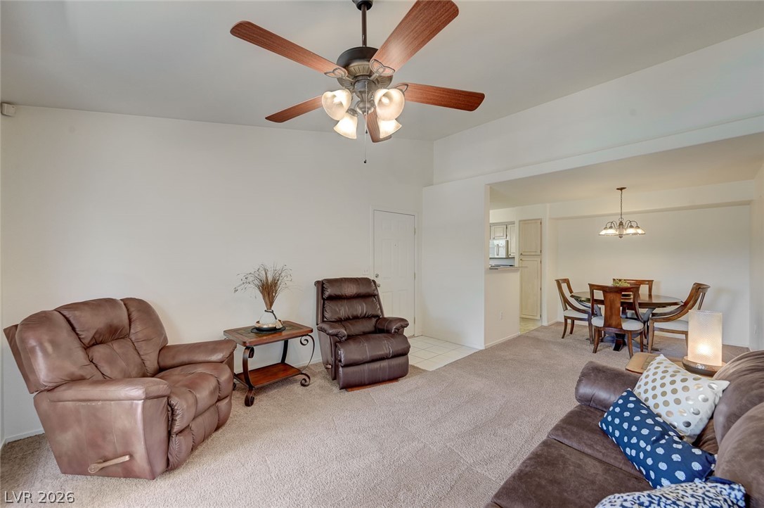 555 East Silverado Ranch Boulevard, Unit 2124 Las Vegas, NV 89183 - Photo 8 of 47 A comfortable living room features a ceiling fan, plush carpeting, and seamless flow into the adjacent dining area.