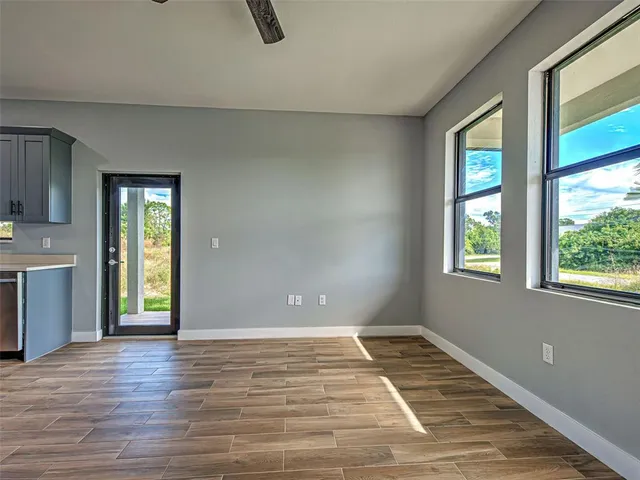 a view of an empty room with window and wooden floor