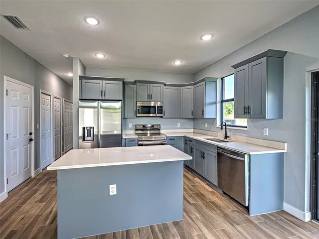 a kitchen with kitchen island a sink appliances and cabinets