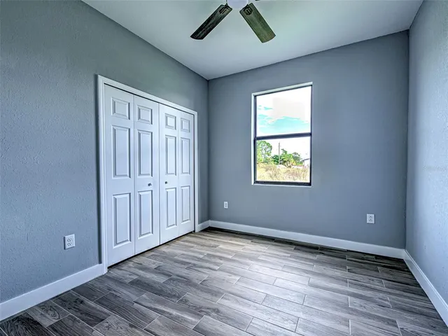 an empty room with wooden floor cabinet and windows