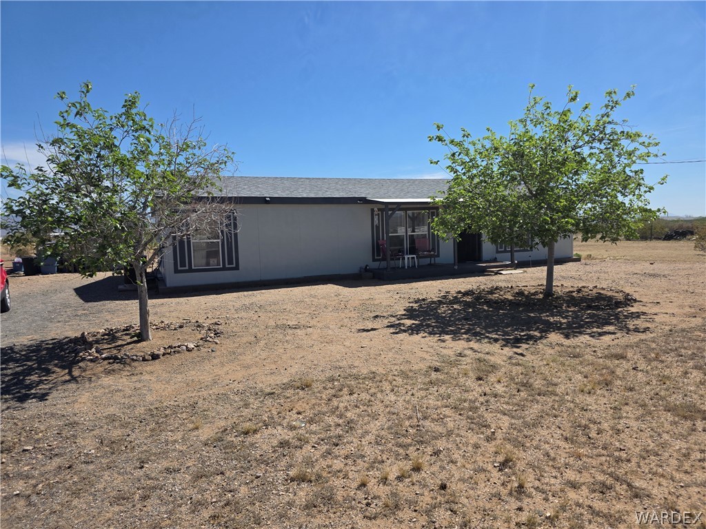 4182 Canelo Road Golden Valley, AZ 86413 - Photo 1 of 31 The property features a light-colored exterior with dark trim, a covered porch, and a gravel driveway