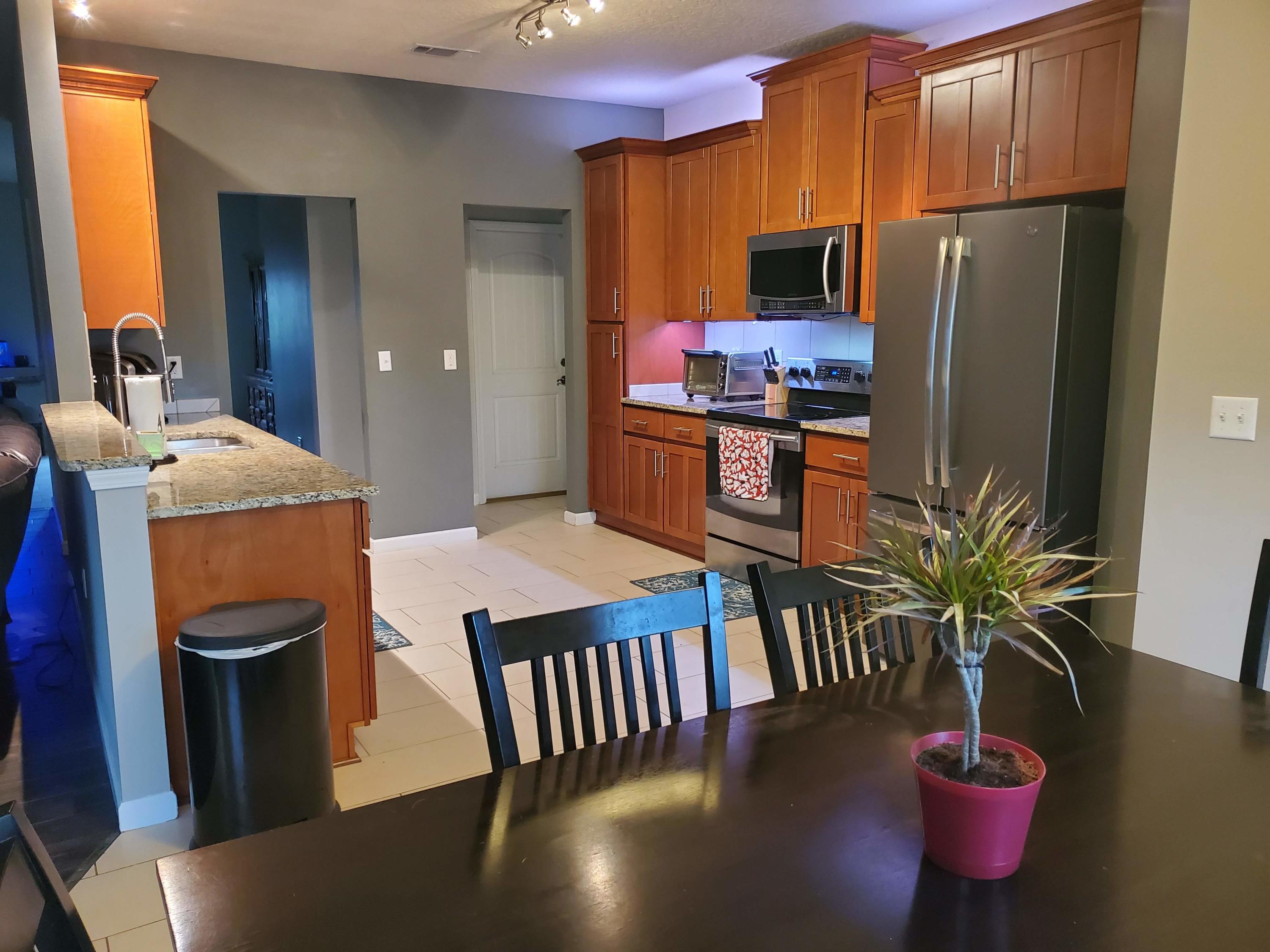 4598 Hermosa Road Crestview, FL 32539 - Photo 22 of 31 a kitchen with stainless steel appliances granite countertop a refrigerator a stove a sink dishwasher with a dining table and chairs