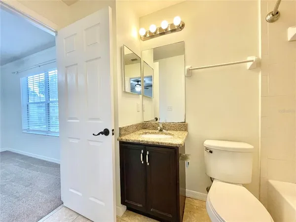 a bathroom with a granite countertop toilet sink and mirror