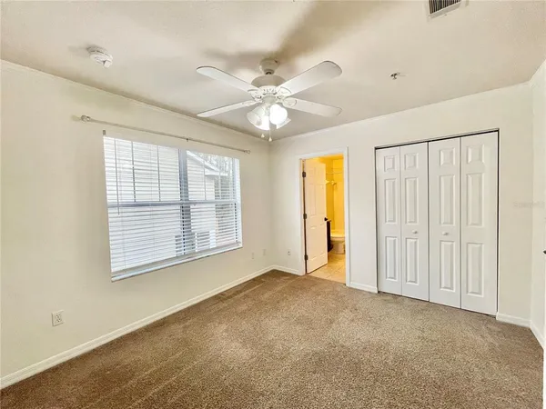 a view of an empty room with a window and a kitchen