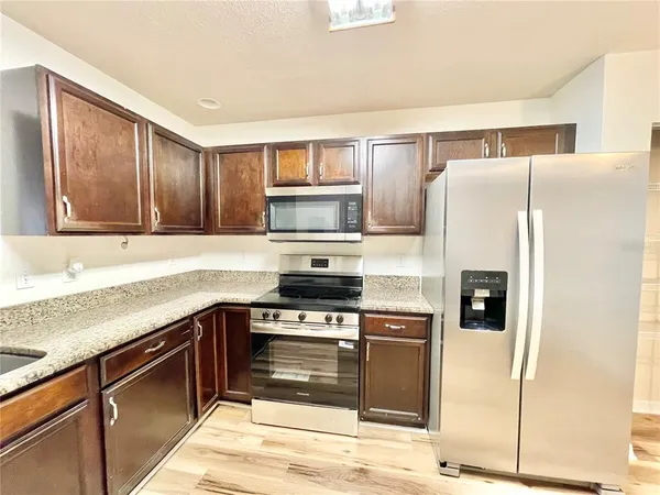 a kitchen with stainless steel appliances granite countertop a refrigerator and a stove top oven