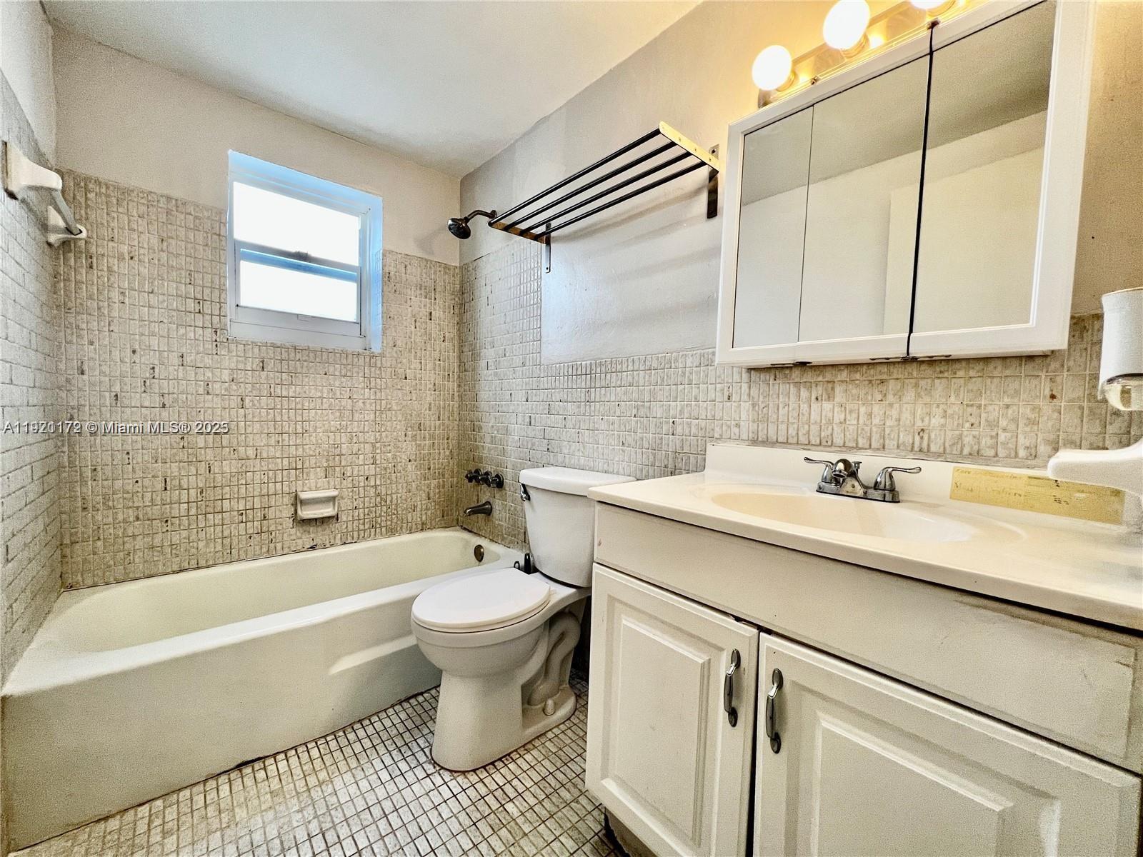 8531 Harding Avenue, Unit 1 Miami Beach, FL 33141 - Photo 9 of 11 a bathroom with a sink a toilet and bathtub
