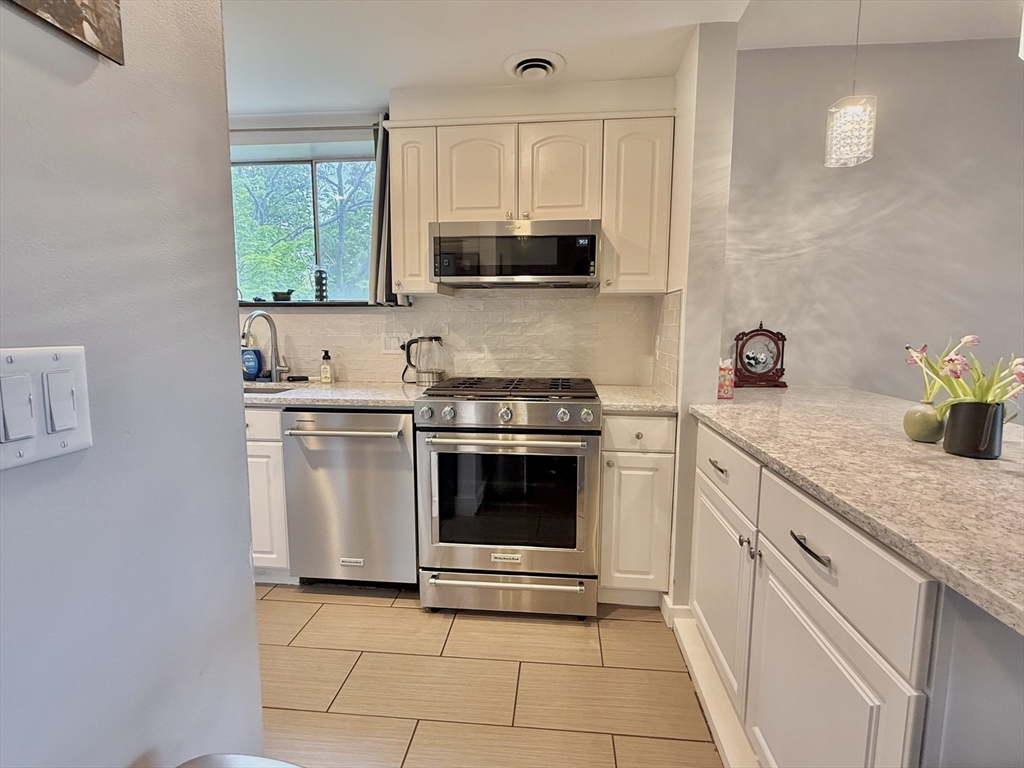 20 Stearns Road, Unit 45 Brookline, MA 02446 - Photo 3 of 22 a kitchen with granite countertop white cabinets and appliances