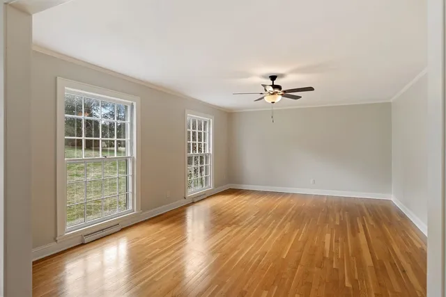 an empty room with wooden floor and windows