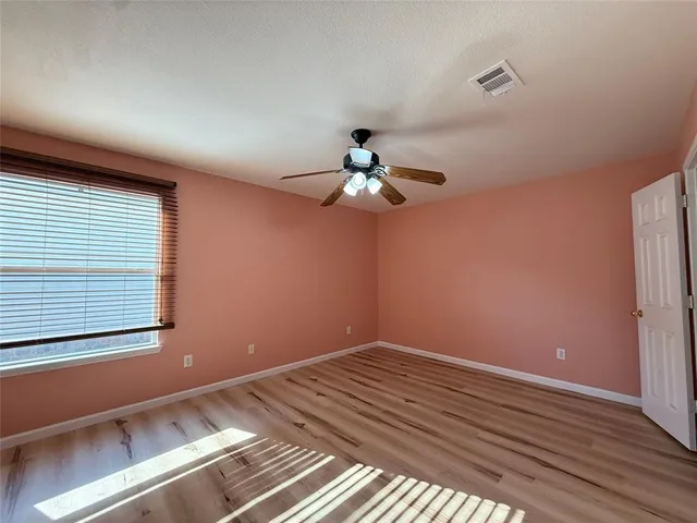 a view of a room with a large window and chandelier fan