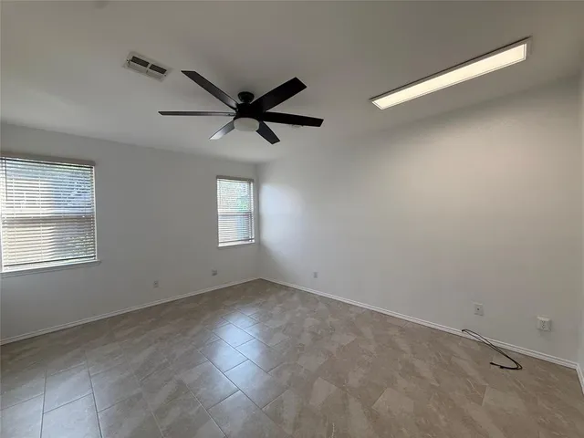 en empty room with windows and ceiling fan