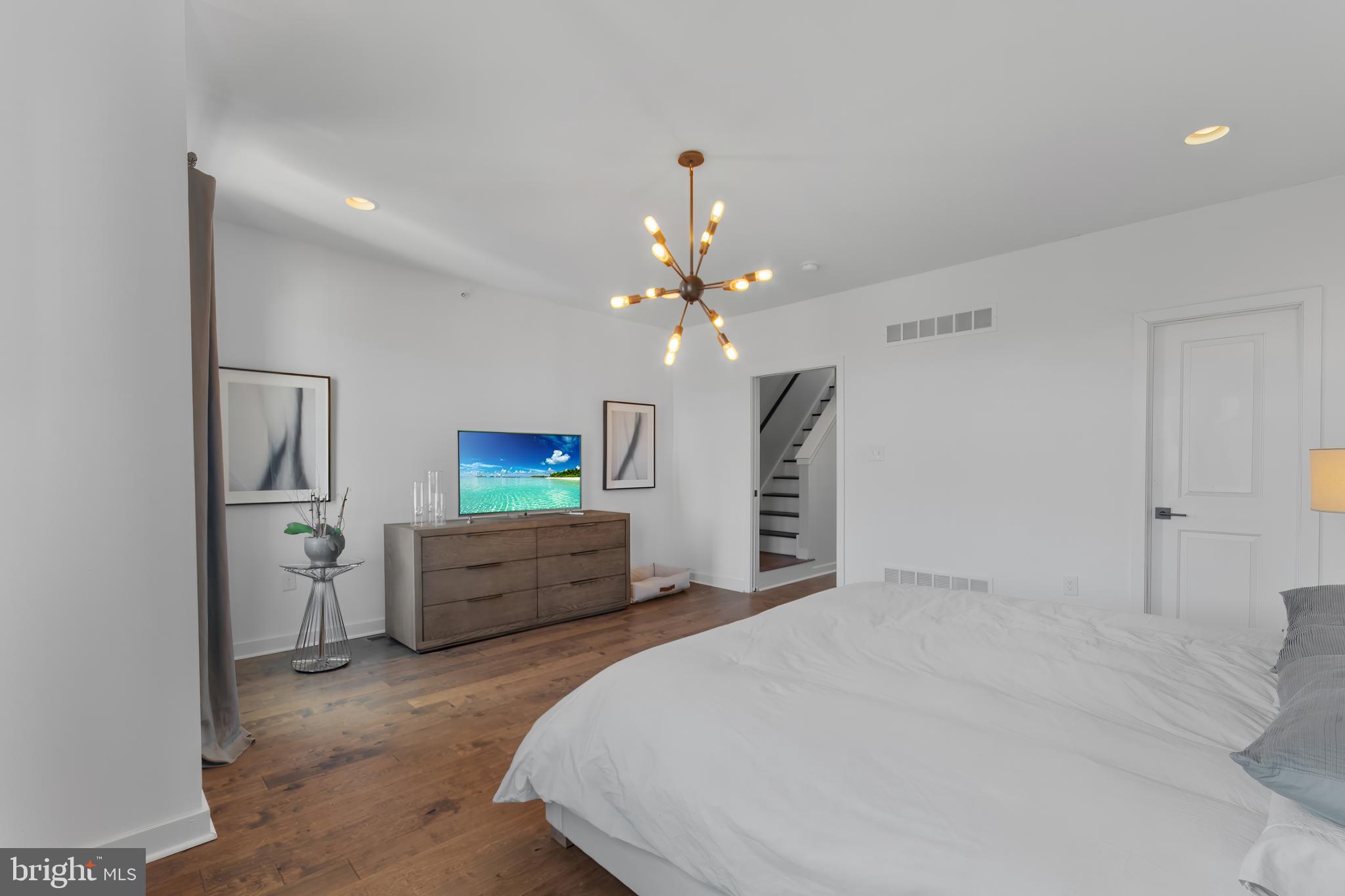 136 Burnside Street Philadelphia, PA 19127 - Photo 20 of 25 a spacious bedroom with a bed and a chandelier
