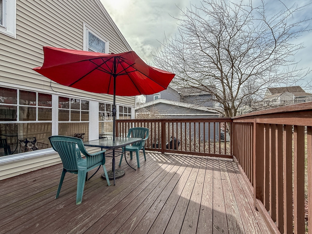 69 Bennett Street Wakefield, MA 01880 - Photo 4 of 27 a view of a deck with table and chairs under an umbrella with wooden floor and fence