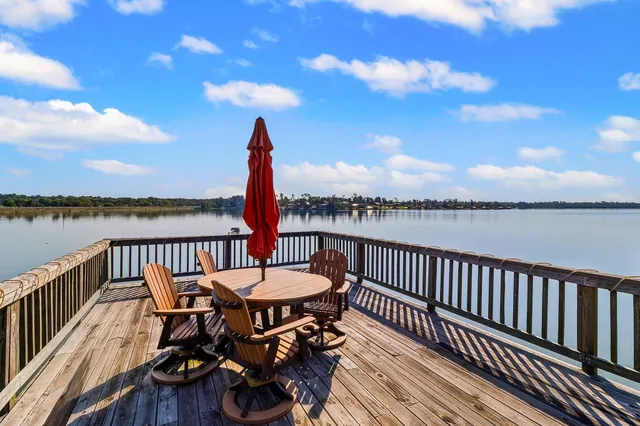 a view of a roof deck with table and chairs with wooden floor and fence