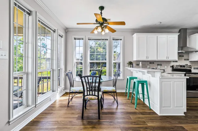 a dining room with wooden floor a chandelier a glass table and chairs