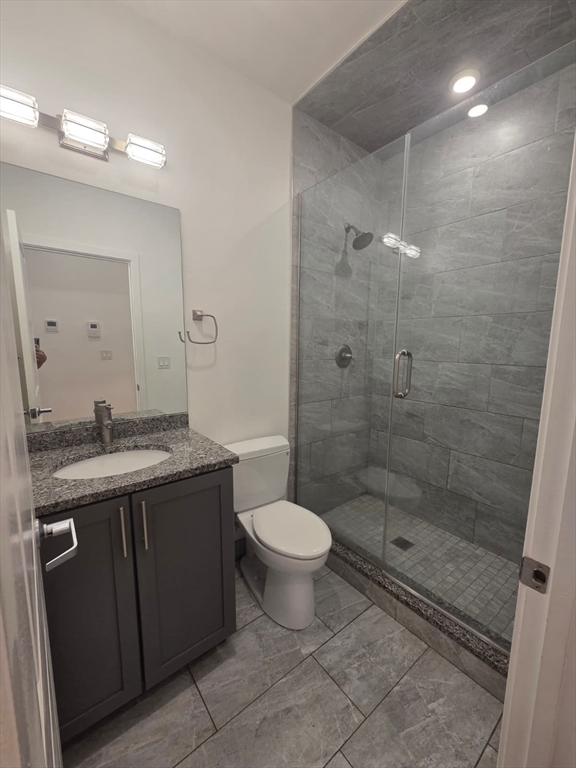 a bathroom with a granite countertop sink a toilet and shower