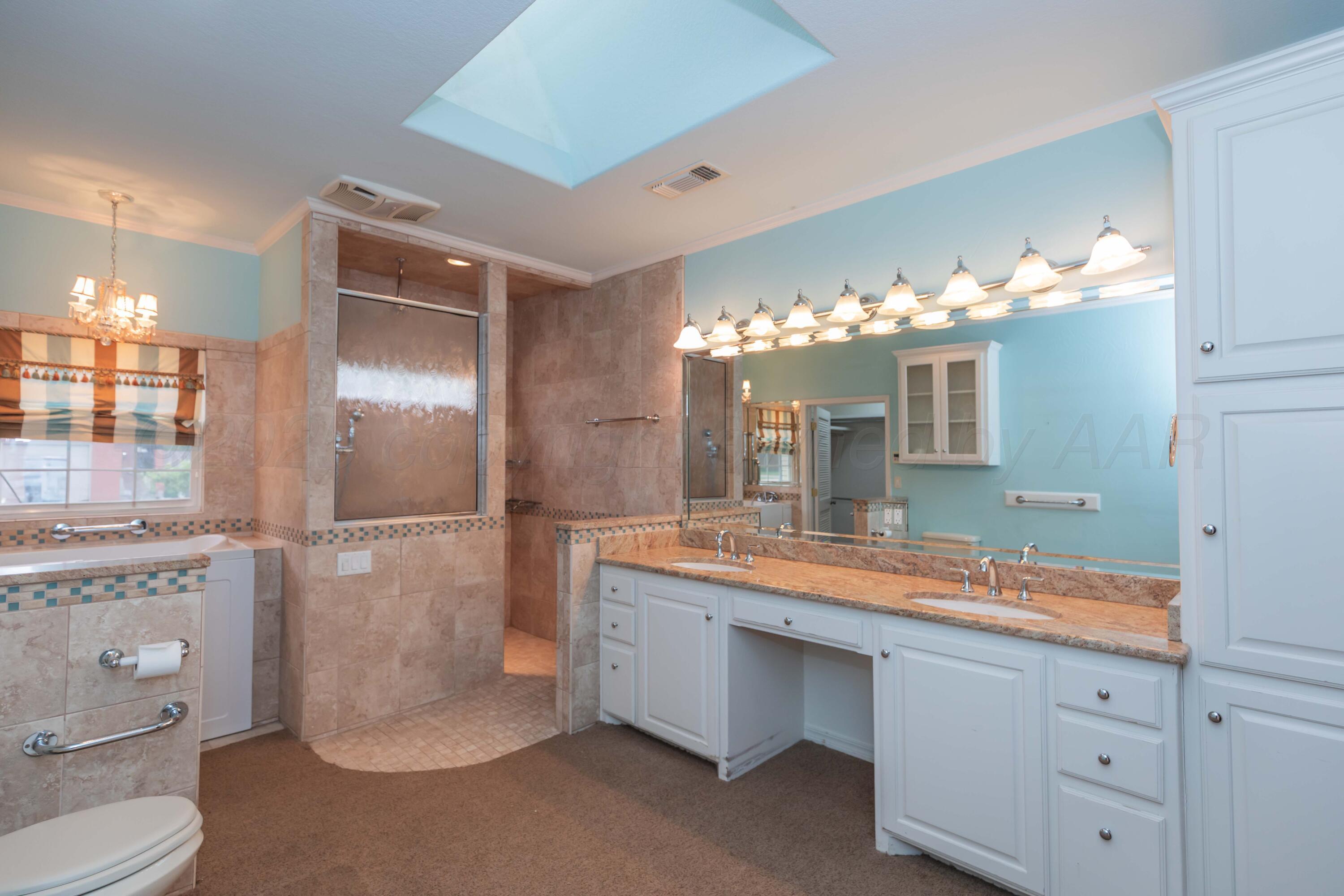 4102 Paramount Boulevard Amarillo, TX 79109 - Photo 61 of 73 a spacious bathroom with a granite countertop sink a toilet and a mirror