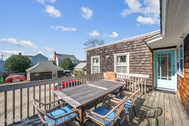 a roof deck with a dining table and chairs with wooden floor