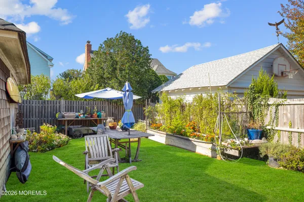 a view of a backyard with couches table and chairs under an umbrella