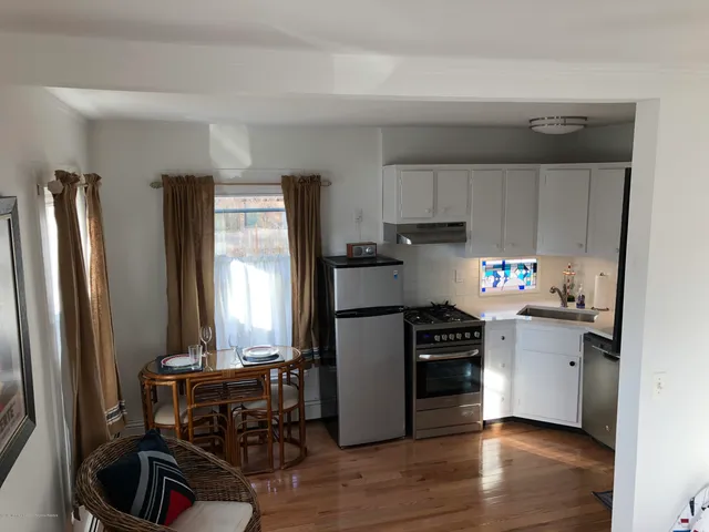a kitchen with a refrigerator a stove and a dining table with wooden floor