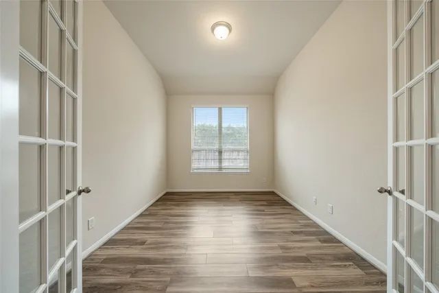 an empty room with wooden floor and windows